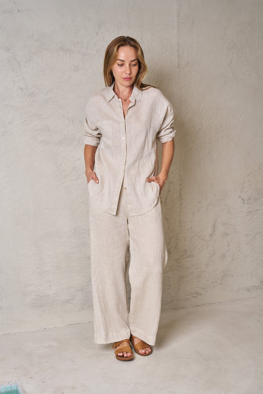 Woman wearing a beige linen outfit against a plain background